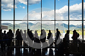 Silhouette queue people waiting in line for airplane in terminal with mountain background