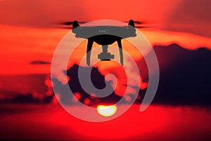 Silhouette of a radio-controlled drone against a red sky. An unmanned aerial vehicle at sunset. The concept of digitalization and
