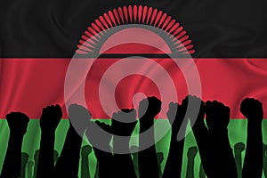Silhouette of raised arms and clenched fists on the background of the flag of Malawi. The concept of power,  conflict. With place