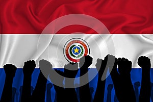 Silhouette of raised arms and clenched fists on the background of the flag of Paraguai. The concept of power,  conflict. With photo