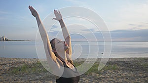 Silhouette rear view of woman doing yoga in tree pose meditating on a rock by the sea with sunset