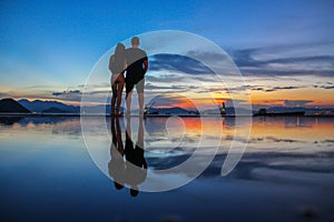 Silhouette and reflection of romantic boy and girl friends holding hands and enjoying sunset at Water front at Western District