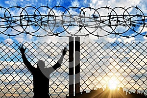 Silhouette of a refugee near the fence