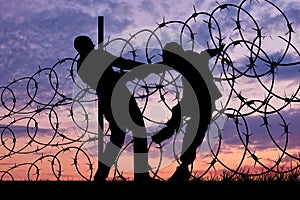 Silhouette of refugees and barbed wire