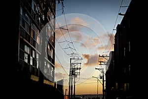 Silhouette of residential buildings and electricity transmission wires against the dramatic late afternoon sky