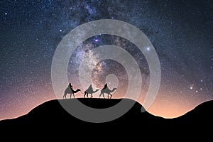 Silhouette of riders on their camels in the desert at night