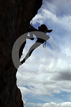 Silhouette of rock climber climbing a cliff