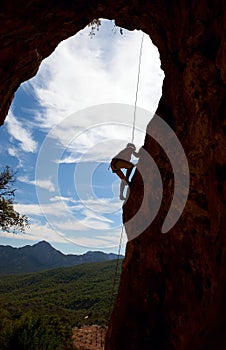 Silhouette of rock climber climbing the cliff