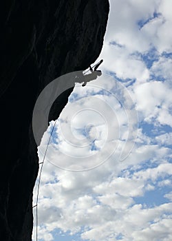 Silhouette of rock climber climbing cliff