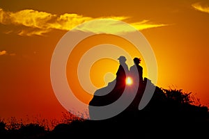 Silhouette of a romance couple looking at the sunset on an orange sky