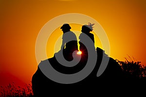 Silhouette of a romance couple looking at the sunset on an orange sky