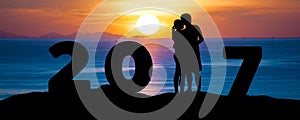 Silhouette of romantic a couple hug kissing against summer sea beach in sunset twilight sky while celebrating happy new year 2017