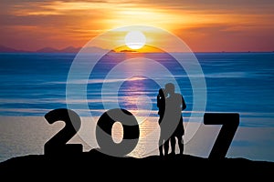 Silhouette of romantic a couple hug kissing against summer sea in sunset twilight sky while celebrating happy new year 2017