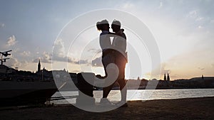 Silhouette of romantic couple hugging and kissing on pier at sunset