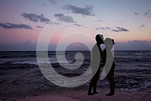 Silhouette romantic couple kissing at the ocean with colorfull sunset