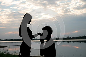 The silhouette of a romantic couple standing, hugging each other and watching the sunset. Romance and love concept