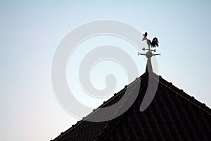 Silhouette of a rooster weather vane on the roof