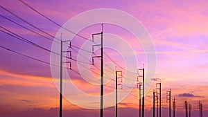 Silhouette row of electric poles with cable lines against colorful sunset sky background
