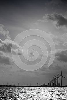 Silhouette of a row of windmills behind each other in the evening