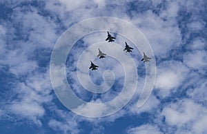 Silhouette of Royal Malaysian Air Force\'s Sukhoi Su-30MKM fly in formation across blue sky with thin clouds.