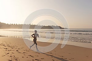 Silhouette of Runner Woman Alone at Early Sunset Outdoors on the Beach