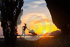 Silhouette of running mother with stroller enjoying motherhood a