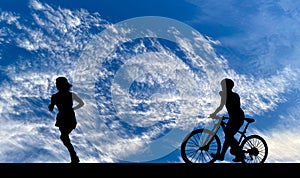 Silhouette of running woman and man riding on modern bike on the road