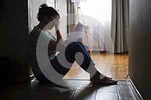 Silhouette of sad and depressed woman sitting on the floor at home