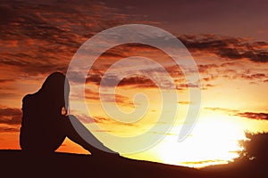 Silhouette sad expression woman sitting alone on top of the hill