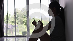 Silhouette of a sad woman sitting in the dark room. Stress, violence, Domestic violence, family problems, The concept of