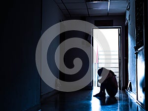 Silhouette of a sad young girl sitting in the dark, thinking about problem with relationships or work, feeling despair and anxiety photo