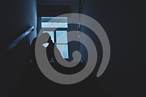 Silhouette Sad young man sitting at the stairs in the dark, Depression and anxiety disorder concept, Life problems, illness,
