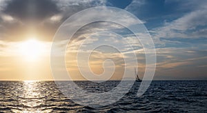 Silhouette Sail boat gliding in open sea at sunset. Tilted monohull in the evening