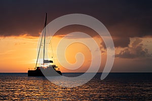 Silhouette of a sail boat sailing off into the of sunset on the distant ocean horizon