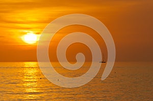 silhouette of a sailboat, motoring through tropical, sunset waters