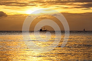 Silhouette of sailing boat on horizon of tropical sunset sea Philippines