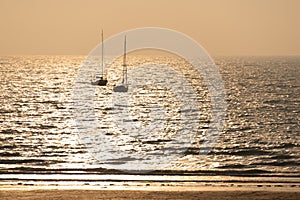 Silhouette of sailing boats at sunset on a beach in PlÃÂ©neuf, CÃÂ´tes d`Armor, Britanny France photo