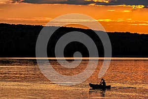 Silhouette of a sailor in a kayak canoe on the lake in the sunset light near an island