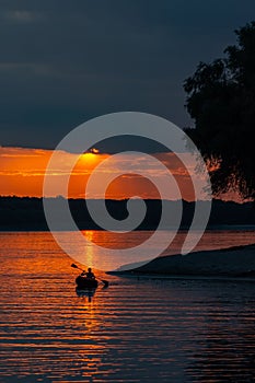 Silhouette of a sailor in a kayak canoe on the lake in the sunset light near an island