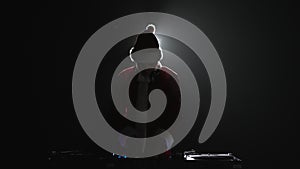 Silhouette of Santa Claus dj playing music on a party in night club. Disc jockey in traditional red Christmas outfit