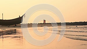 Silhouette sea beach soft water wave nature sunset with background of boat and defocused couple walking