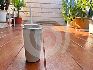 Silhouette selective focus vacuum white coffee glass on the wooden floor at house terrace