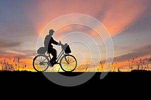 Silhouette of Senior Asian man riding a bicycle at sunset in evening time