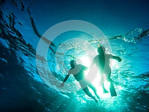 Silhouette of senior couple swimming together in tropical sea