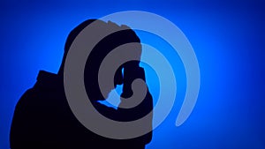 Silhouette of senior frustrated man. Sad male`s face in profile in despair on blue background