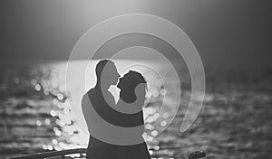 Silhouette of sensual couple kissing with sunset above sea surface on background. Couple in love on romantic date in