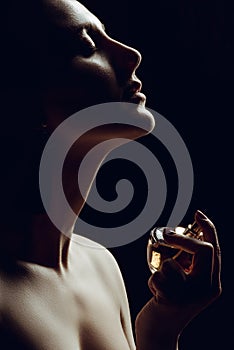 silhouette of sensual girl spraying perfume on neck
