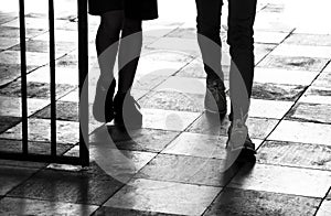 Silhouette shadow of two teenage boys walking through the gate, detail of legs in black and white