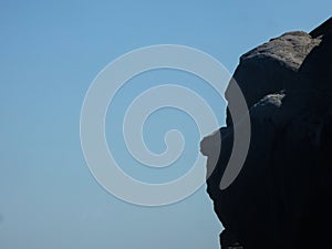 Silhouette shot of half of the face of a Buddha statue on a blue sky background