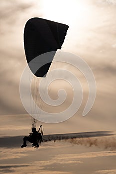 Silhouette shot of a man parachuting during sunset